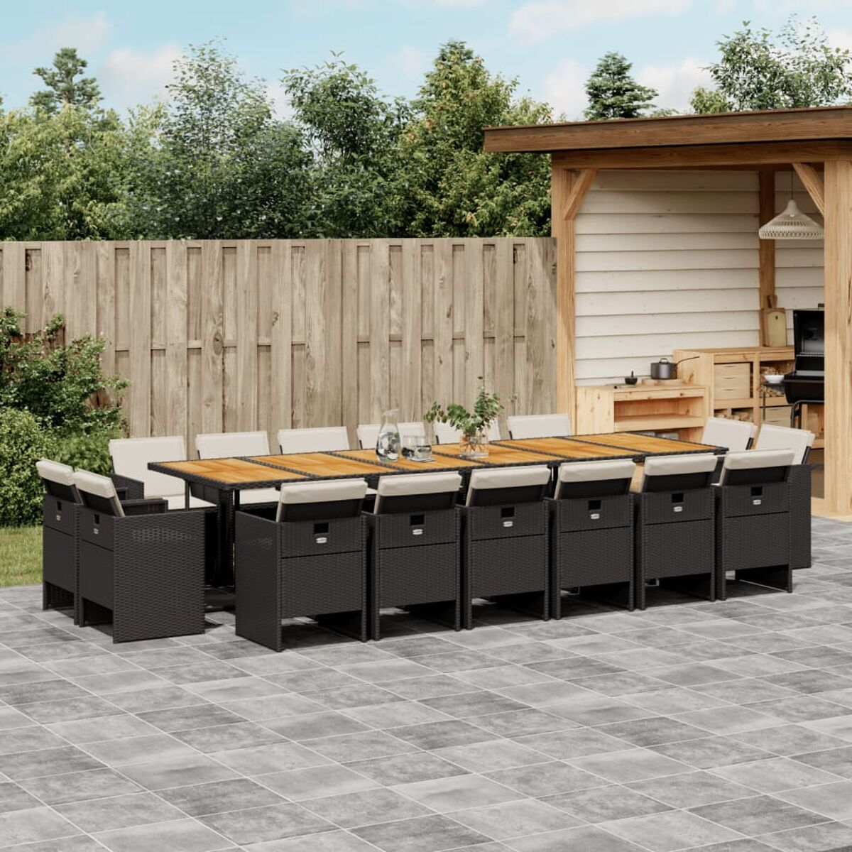 Großes schwarzes Outdoor-Essset aus Korbgeflecht mit Holztisch und cremefarbenen Kissen.
