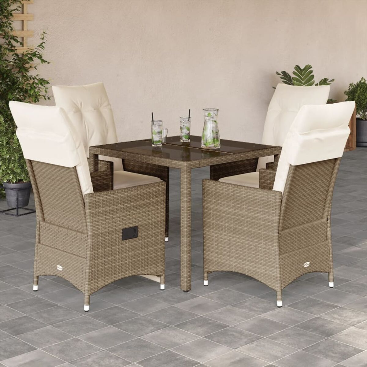 Ein Tisch und vier Stühle mit cremefarbenen Kissen auf einer Terrasse.