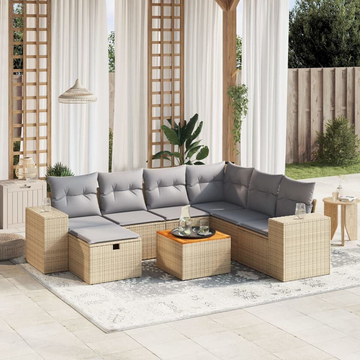 Outdoor-Sofagarnitur aus beigem Korbgeflecht, graue Kissen, Holztisch, gemusterter Teppich und Pergola.
