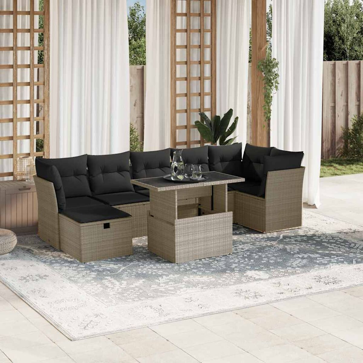 Rattan-Ecksofa mit schwarzen Kissen, einem Tisch mit Hubfunktion und einem Teppich.