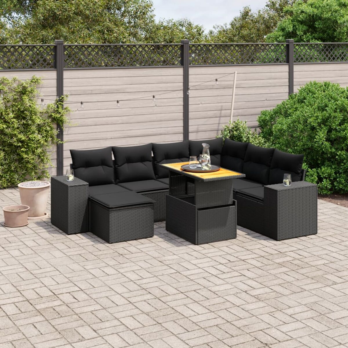 Outdoor-Sitzgruppe mit schwarzen Kissen, einem höhenverstellbaren Couchtisch und einer Terrasse.