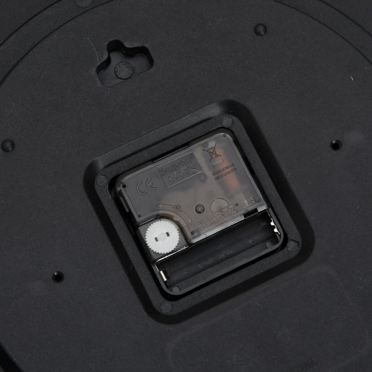 Die Rückseite eines Uhrwerks. Quarz. Eine Batterie befindet sich im Batteriefach. Schwarzer Hintergrund.