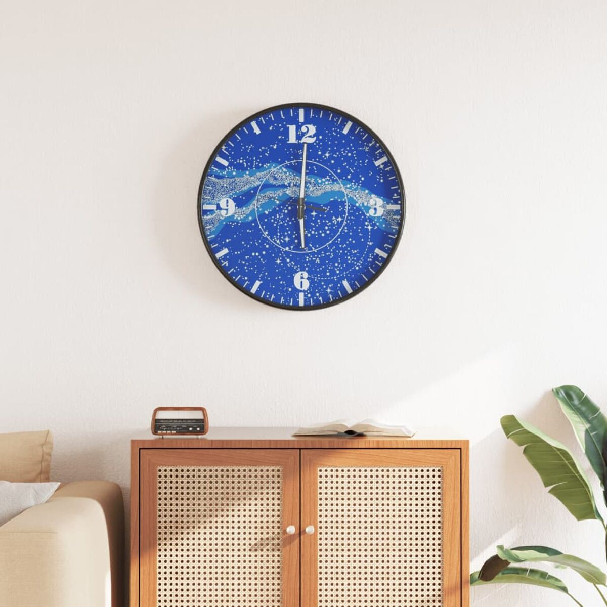 Eine blau-weiße Uhr mit Sternenmuster hängt an einer weißen Wand über einem Holzschrank.