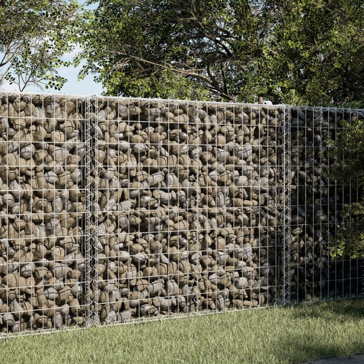 Steinmauer aus in Drahtgeflecht eingeschlossenen Felsen, mit grünem Gras und Bäumen.