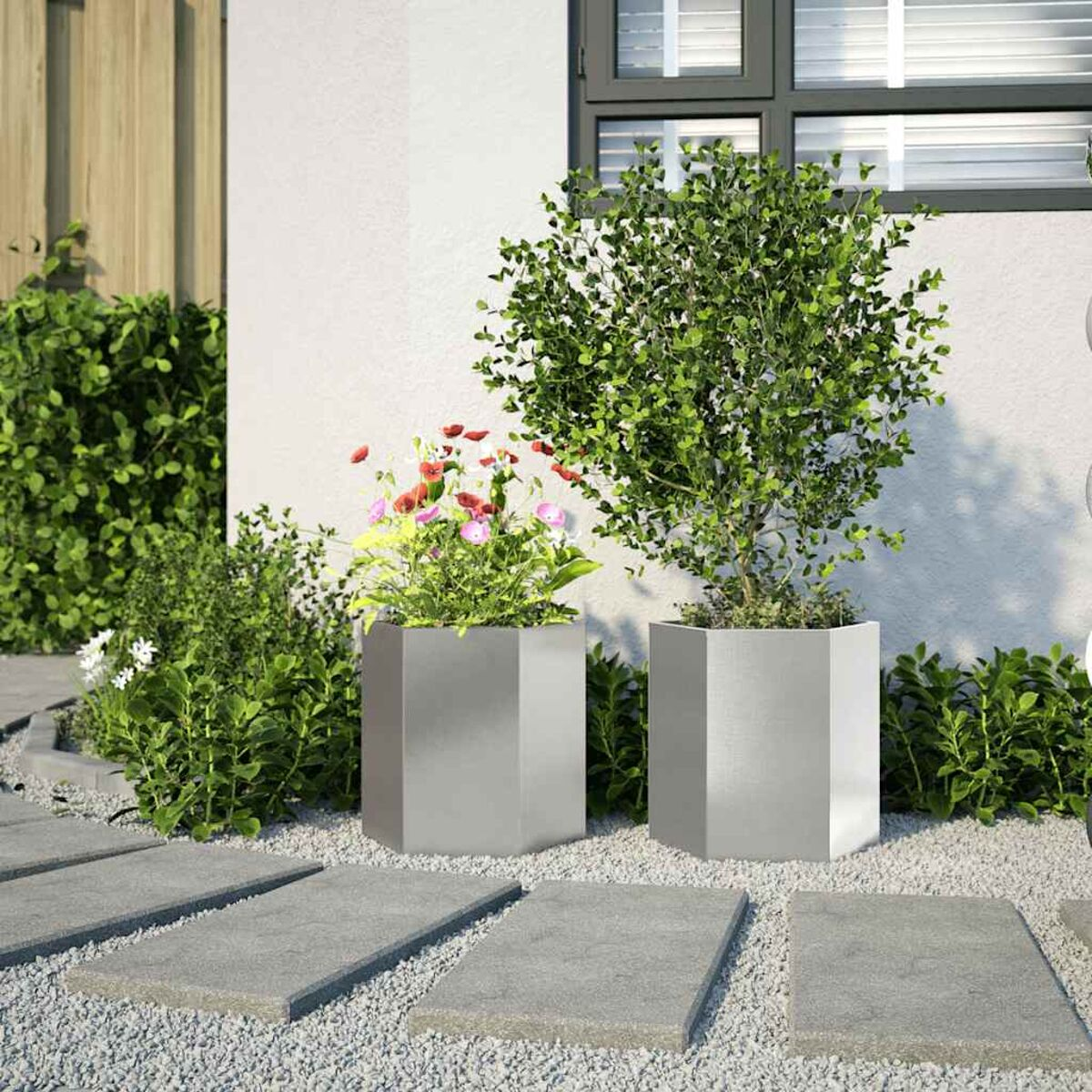 Zwei graue Pflanzgefäße mit Pflanzen, umgeben von Kieselsteinen und Steinplatten.