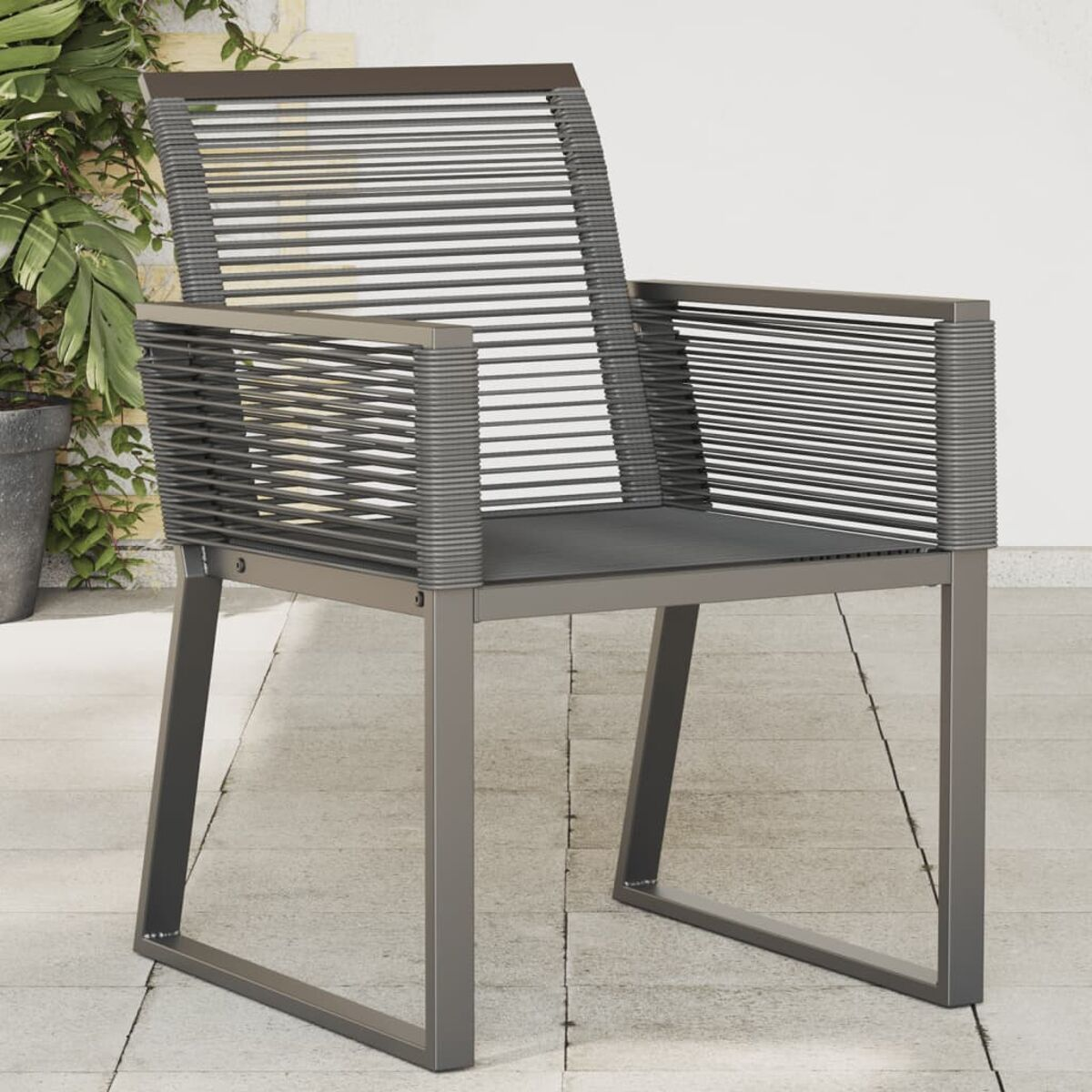 Sedia in metallo grigio con dettagli intrecciati neri, su un patio esterno piastrellato.