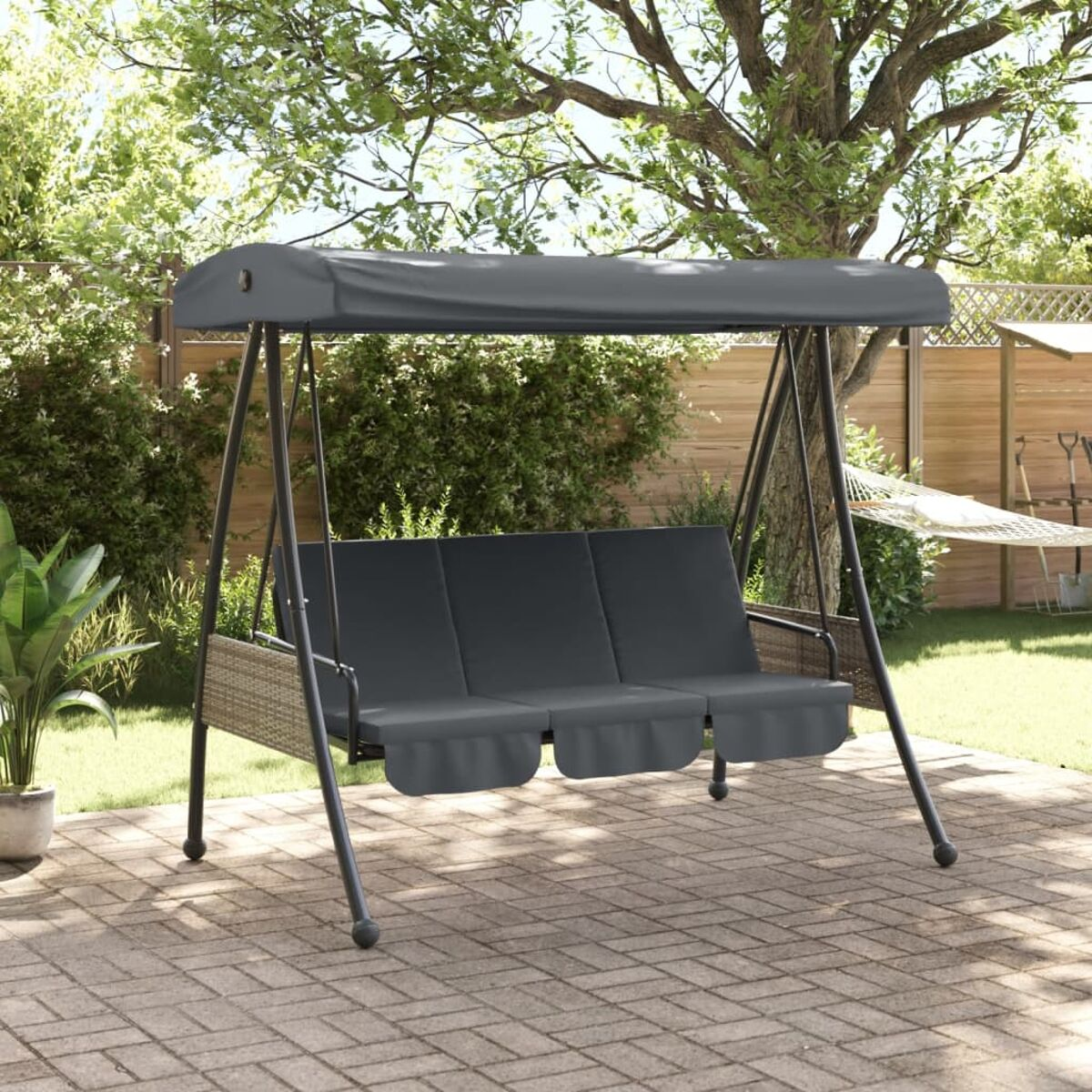 Eine graue Schaukel im Garten mit einem Verdeck. Enthält Schaukel, Kissen und einen gepflasterten Boden.