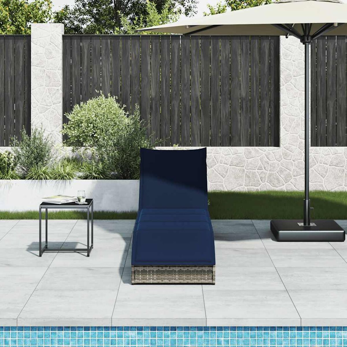 Sdraio con cuscino blu, tavolino e ombrellone, vicino alla piscina.