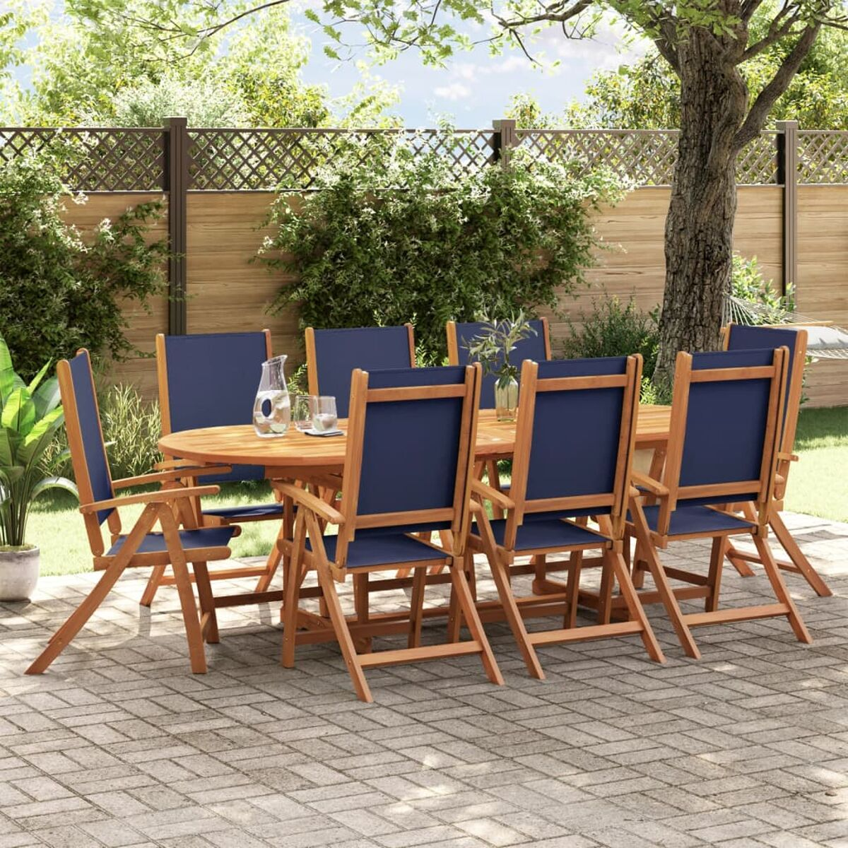Juego de mesa y sillas de madera en un jardín. Mesa con cristal y jarra. Sillas azules.