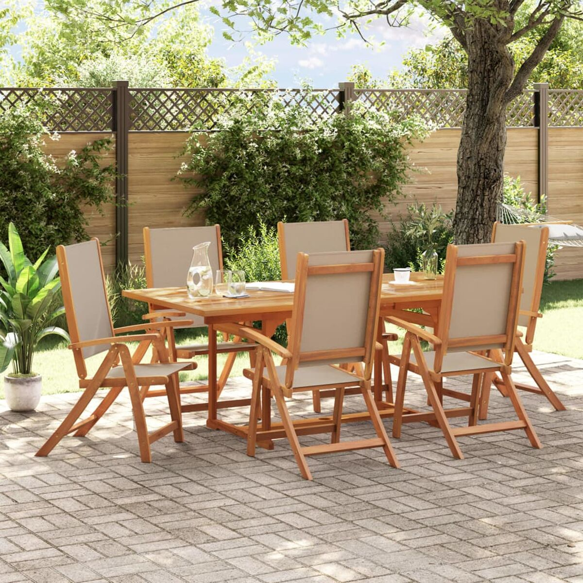 Esstisch aus Holz im Freien mit sechs Stühlen mit beigem Sitz auf einer Ziegelterrasse, unter einem Baum.