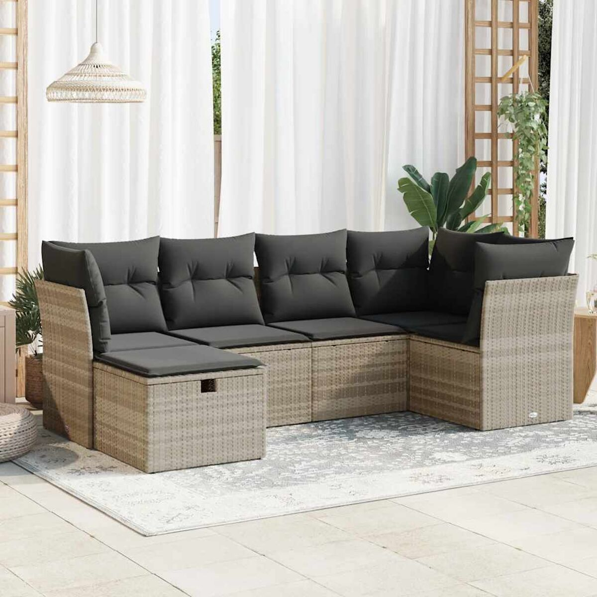 Outdoor-Ecksofa mit grauen Kissen auf einer grauen Terrasse. Weiße Vorhänge im Hintergrund.