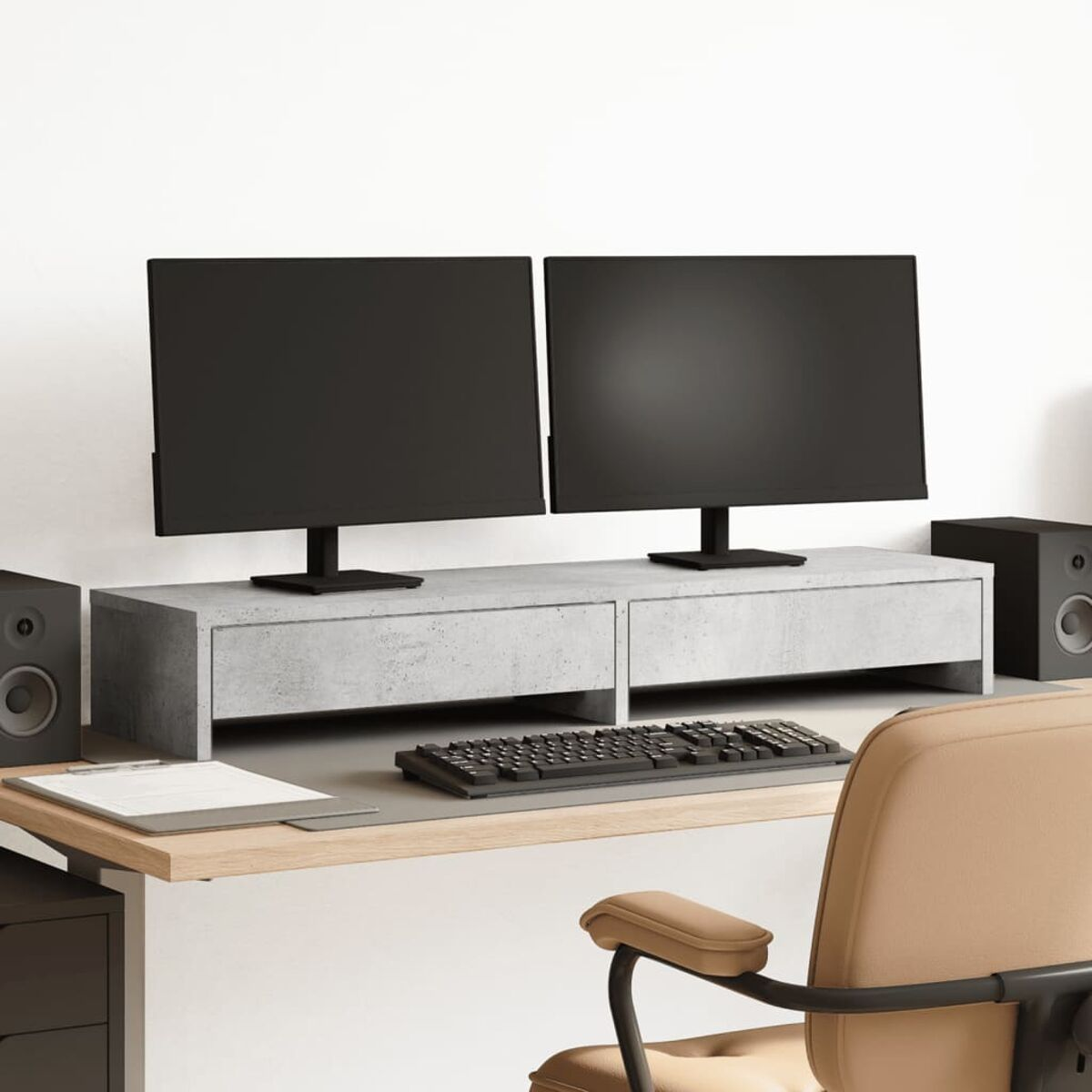 Ein Schreibtisch mit zwei Monitoren, einer Tastatur und Lautsprechern. Der Schreibtisch ist helles Holz, und der Hintergrund ist eine weiße Wand.