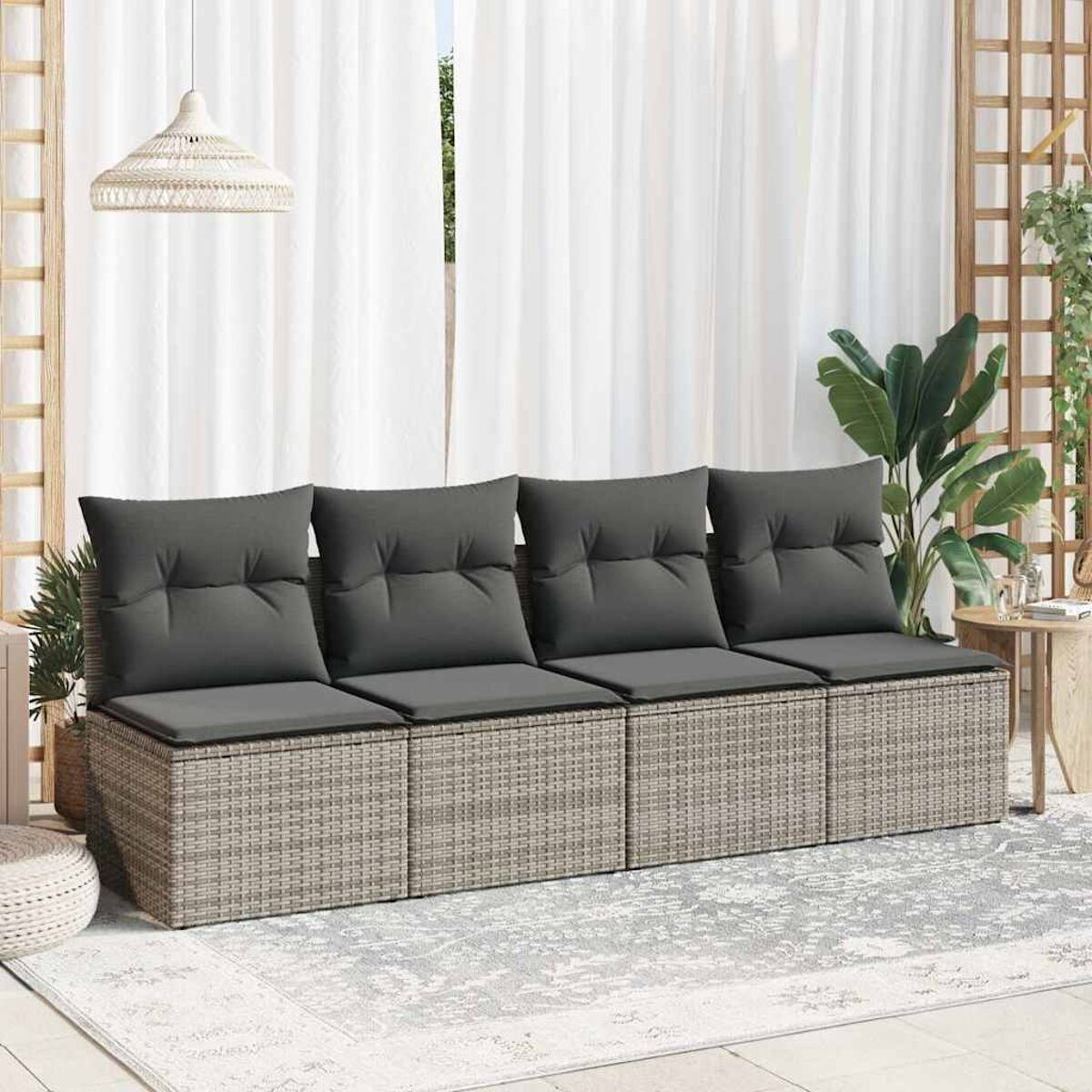 Divano in rattan grigio con cuscini grigi, su un tappeto grigio con tende bianche.