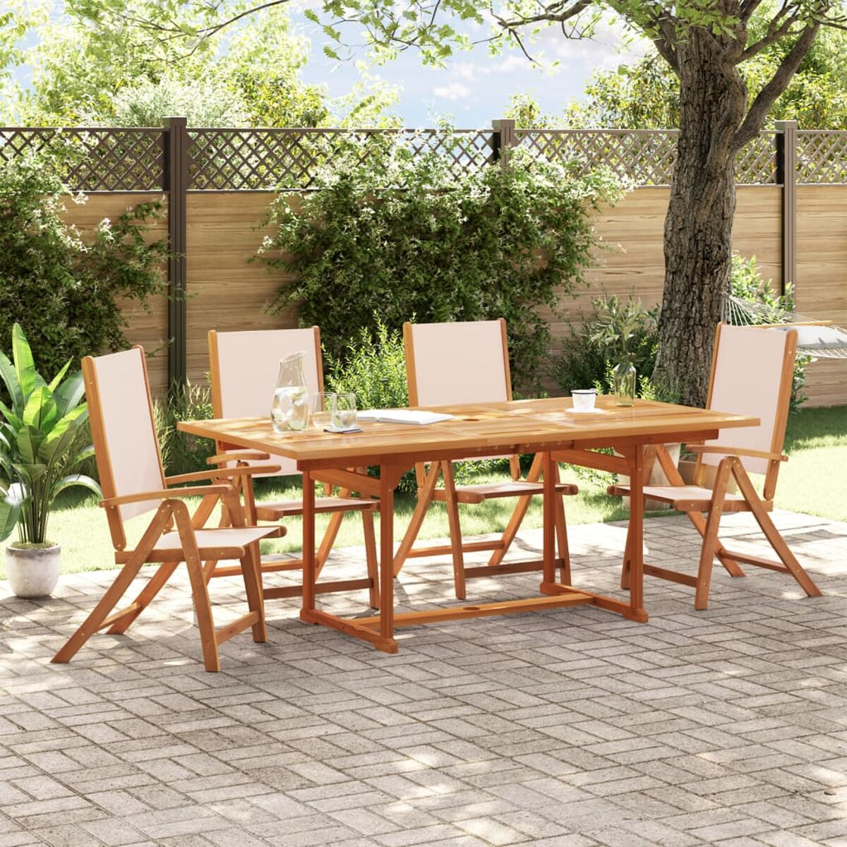 Holztisch und Stühle für die Terrasse. Die Umgebung ist ein Garten mit Grün.
