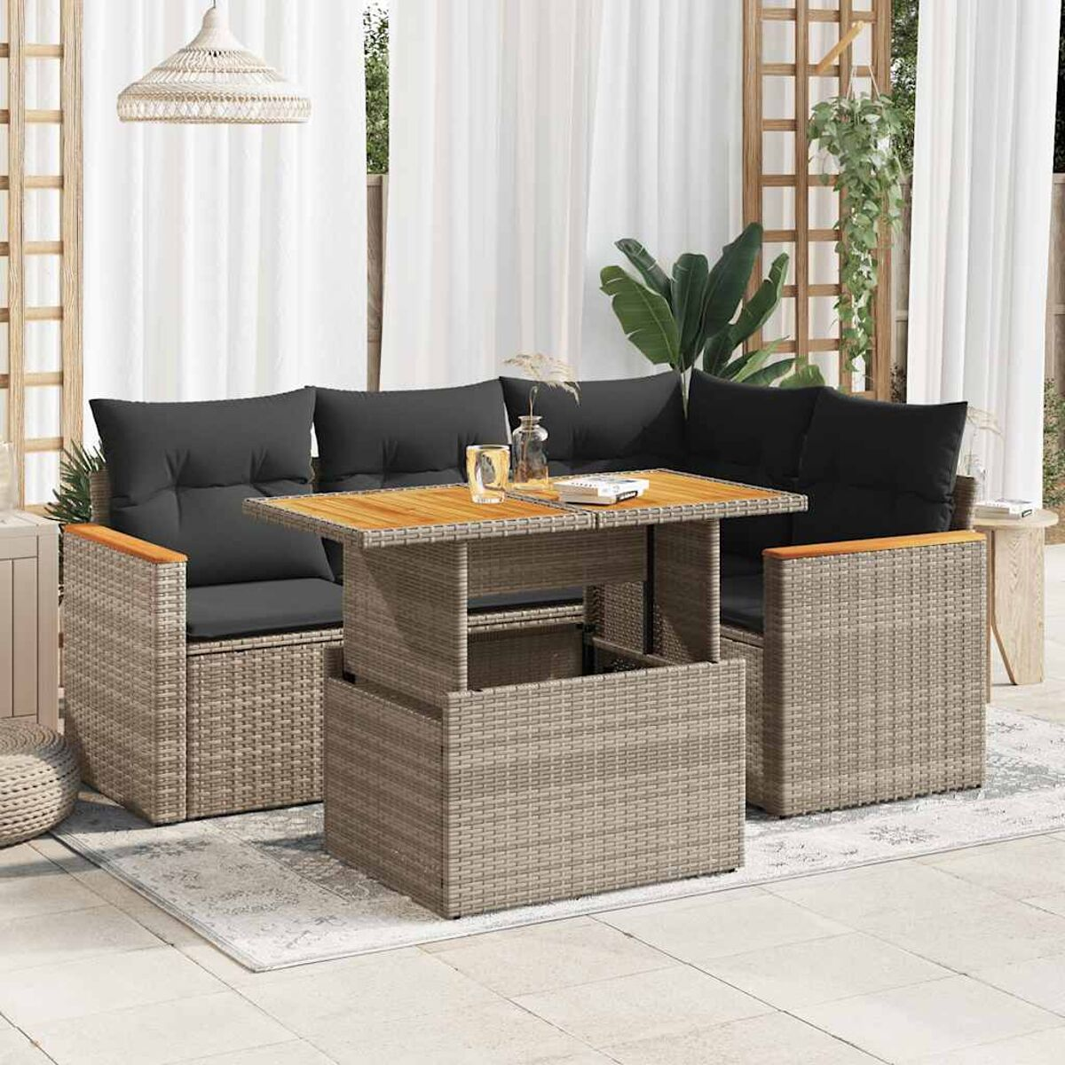 Geflochtene Sitzgruppe für draußen mit Tisch. Graue Kissen und helle Holzakzente.