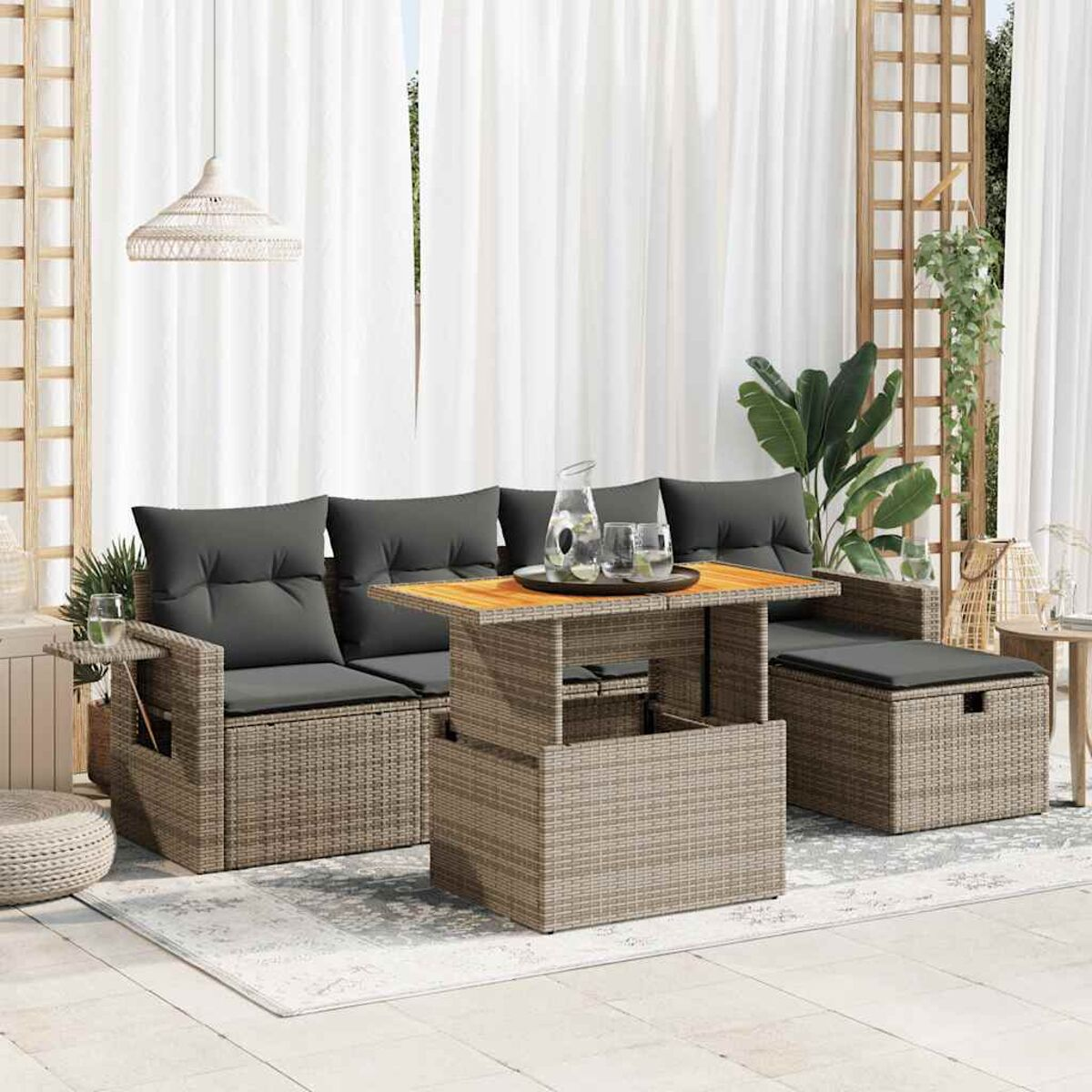 Geflochtenes Outdoor-Möbelset. Enthält Sofa, Tisch und Ottomane. Weiße Vorhänge im Hintergrund.