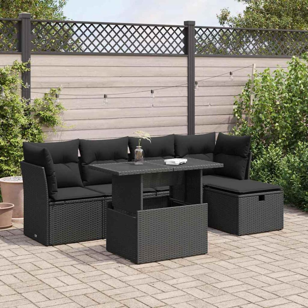 Rattan-Garnitur für den Außenbereich mit Tisch und schwarzen Kissen.