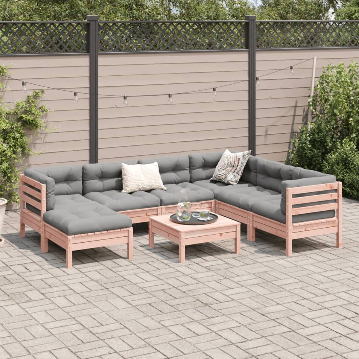 Outdoor-Ecksofa-Set mit grauen Kissen auf einer Steinterrasse, Lichter im Hintergrund.