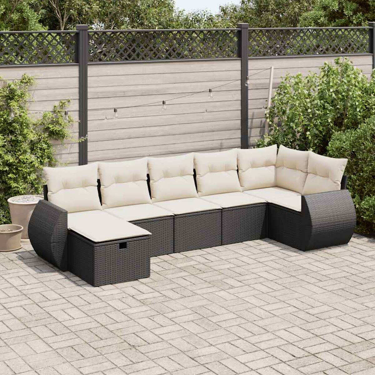 Un moderno divano componibile da esterno con cuscini color crema su un patio in mattoni.