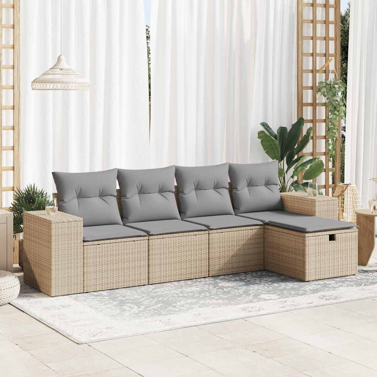 Divano componibile in rattan beige con cuscini grigi su un patio. Sfondo: tende e piante.