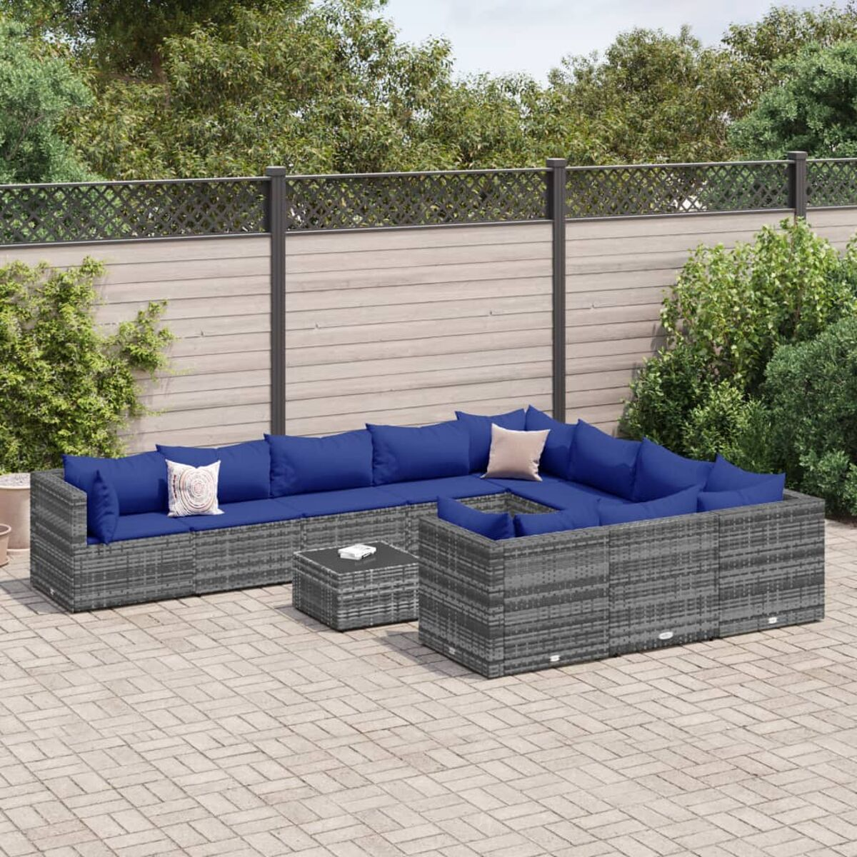 Graue Outdoor-Eckcouch aus Rattan mit blauen Kissen und einem kleinen quadratischen Tisch auf einer Terrasse.
