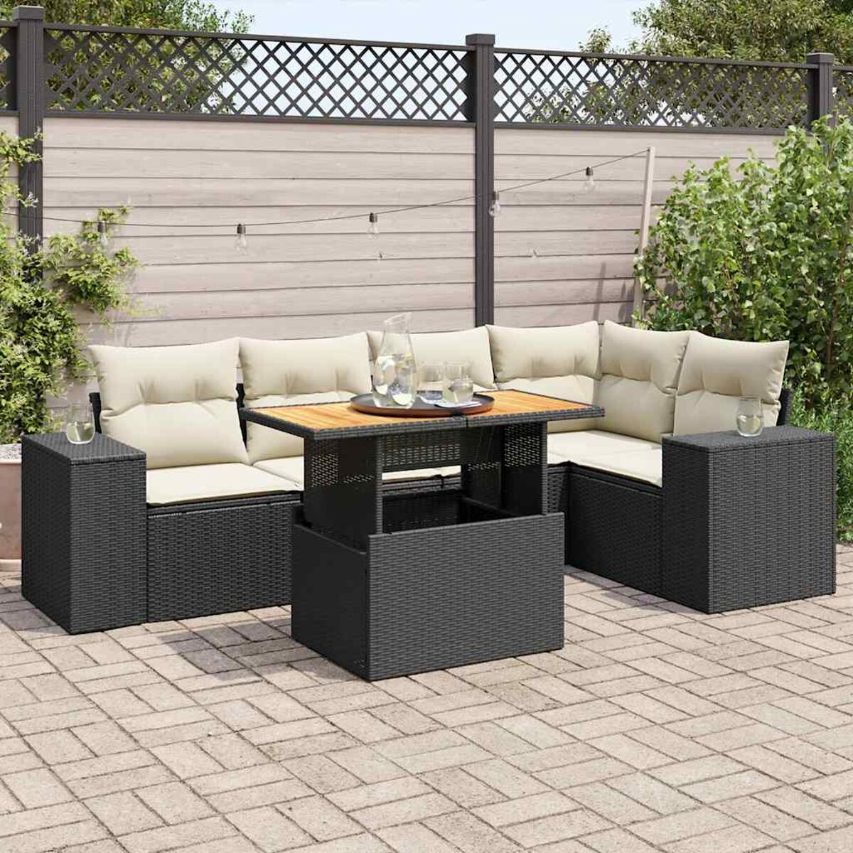 Set divano da esterno in vimini nero con tavolo. Cuscini beige e piano in legno.