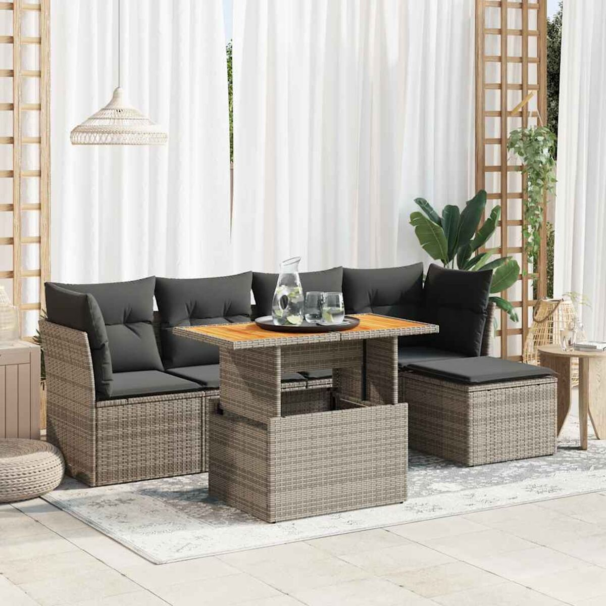 Un set di mobili da esterno in rattan grigio con cuscini neri e un tavolo in legno con bevande.