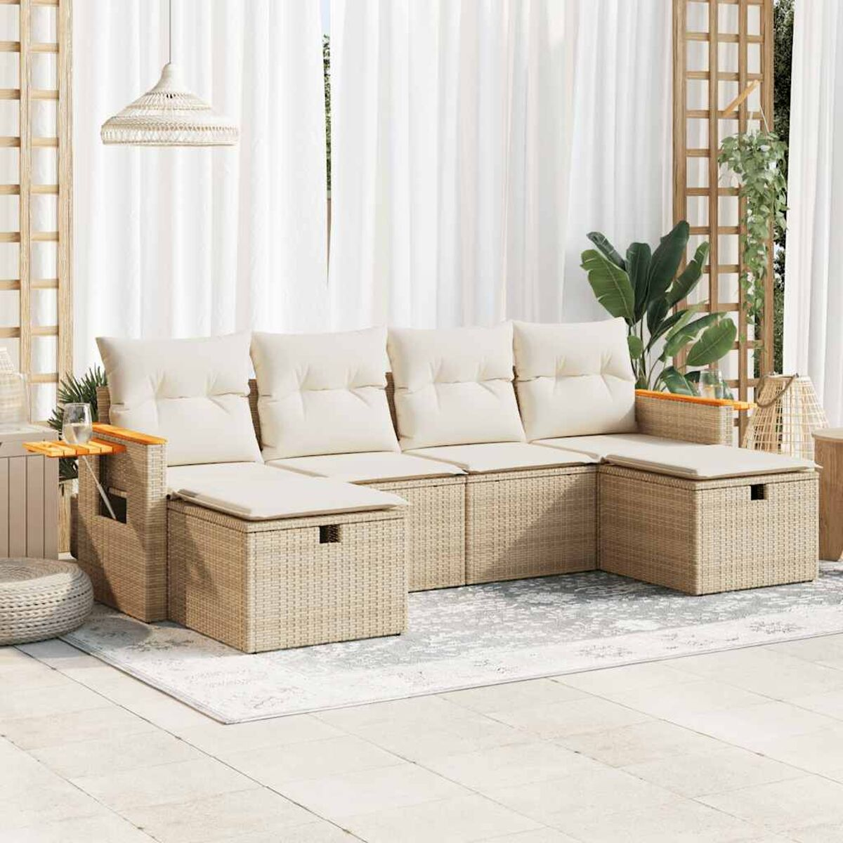 Divano da esterno in vimini con cuscini color crema, tavolino e poggiapiedi. Tonalità neutre, luce naturale, design moderno.