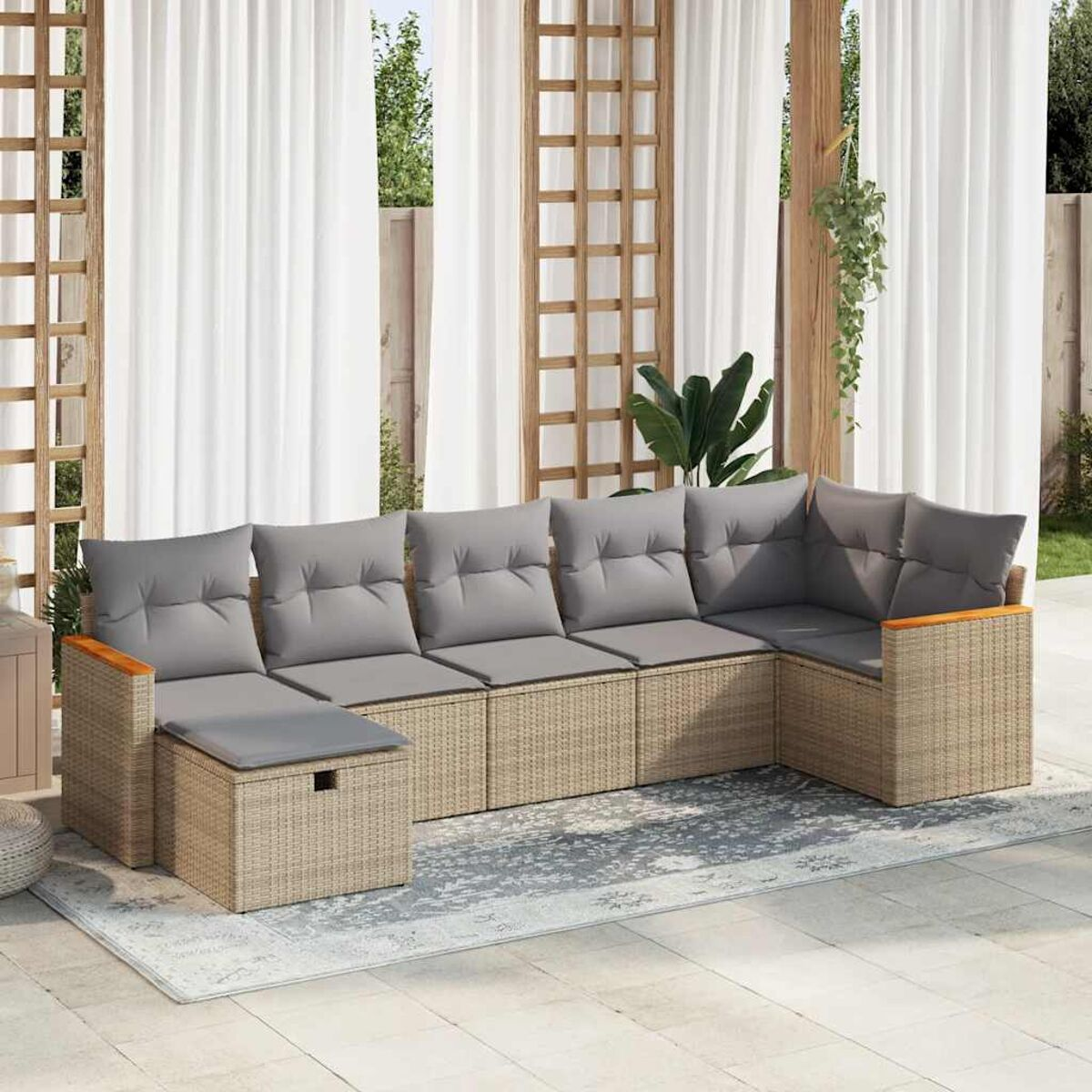 Rattansofa im Freien mit grauen Kissen. Grauer Teppich, Holzdetails, weiße Vorhänge.
