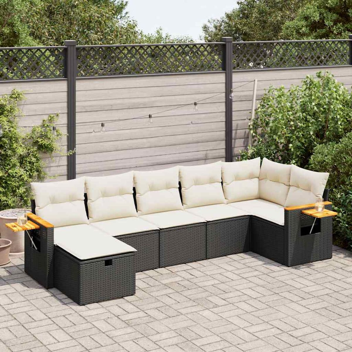 Dunkelgraues Outdoor-Ecksofa mit cremefarbenen Kissen, auf einer Ziegelterrasse.