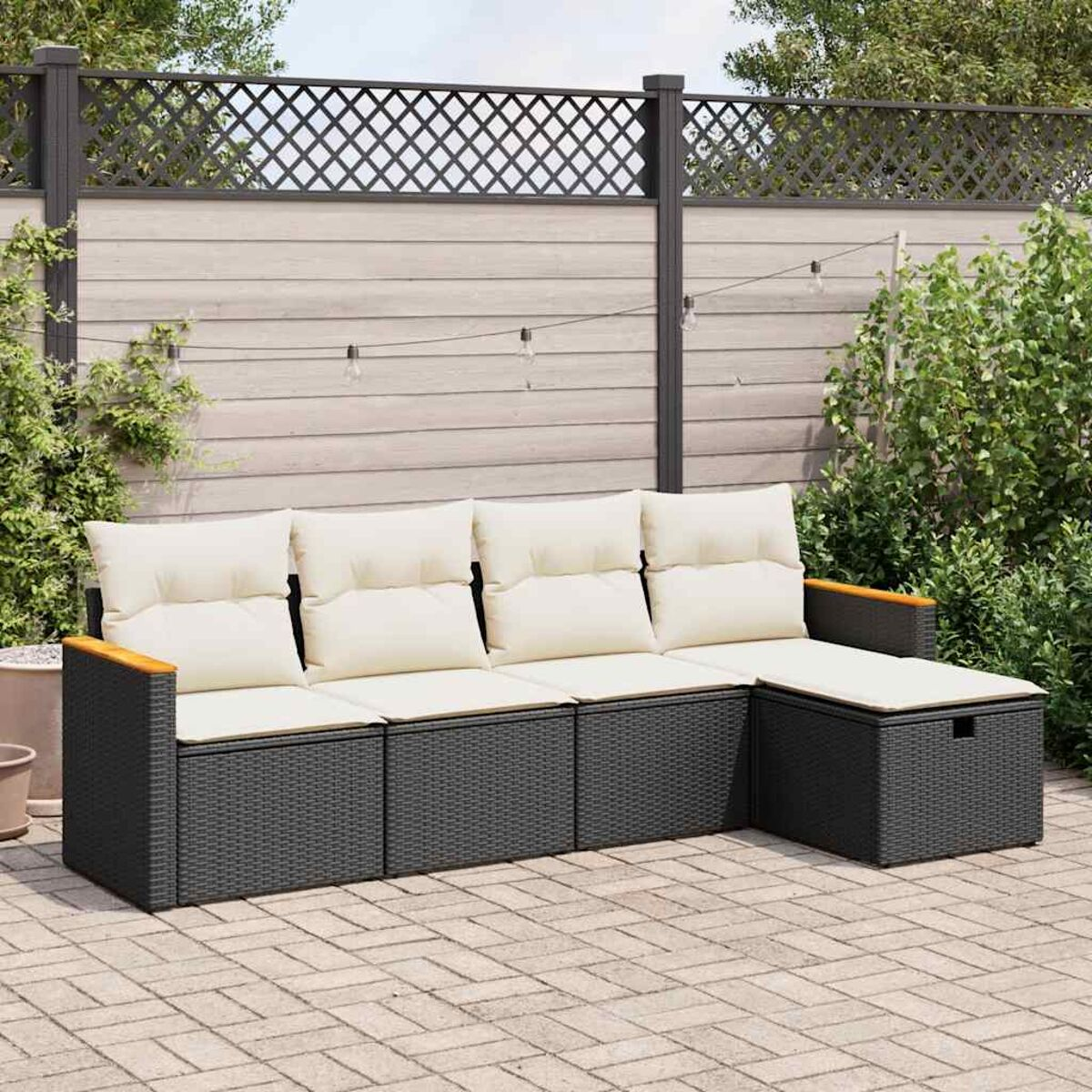 Schwarzes Ecksofa aus Rattan mit cremefarbenen Kissen. Umgebung im Freien.