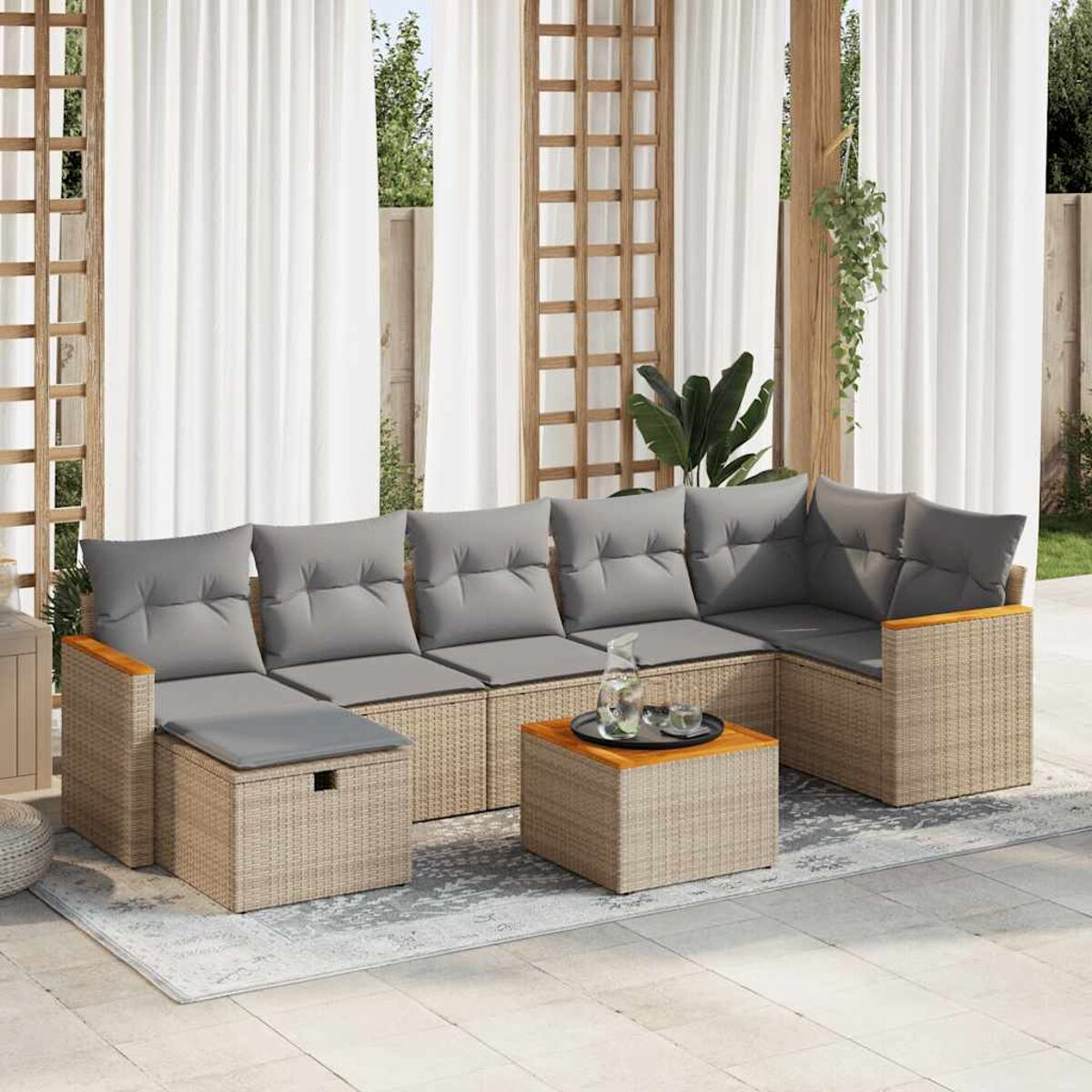 Graues Outdoor-Wicker-Ecksofa mit Kissen und Tisch. Auf einer Terrasse mit Vorhängen und einem Teppich.