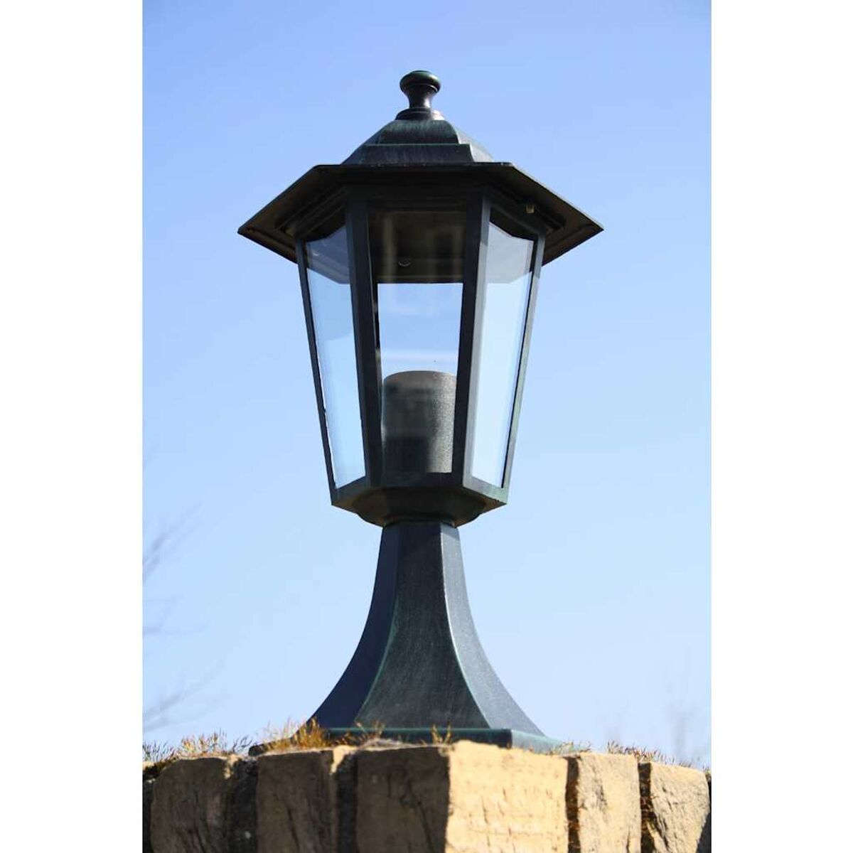 Eine schwarze und bronzefarbene Außenlaterne. Die Glasscheiben umschließen eine Lichtquelle.