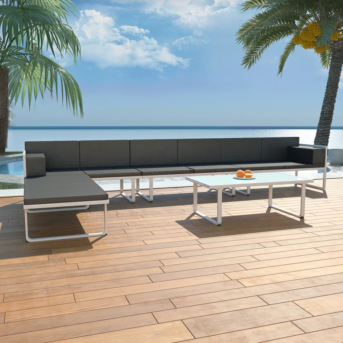 Eine Szene im Freien mit einem schwarzen Sofa, einem weißen Tisch und Palmen auf einem Holzdeck.
