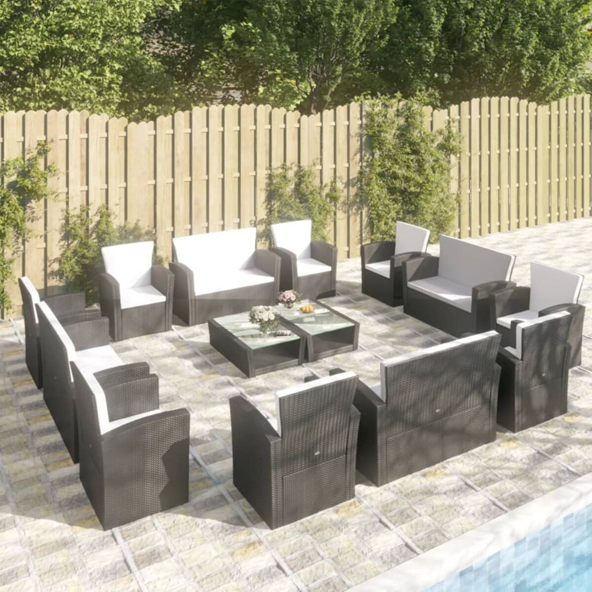Outdoor-Sitzarrangement: eine Gruppe schwarzer Korbstühle und Sofas um einen Tisch.