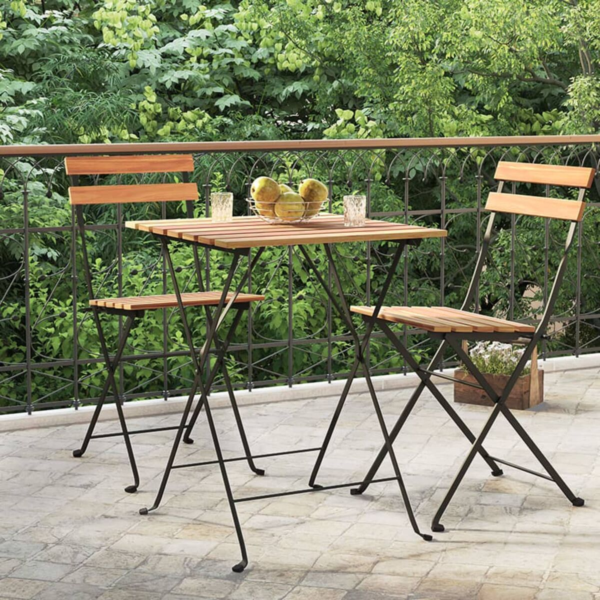 Ein kleines Tisch- und Stuhl-Set auf einem Balkon. Auf dem Tisch sind Früchte und Gläser.