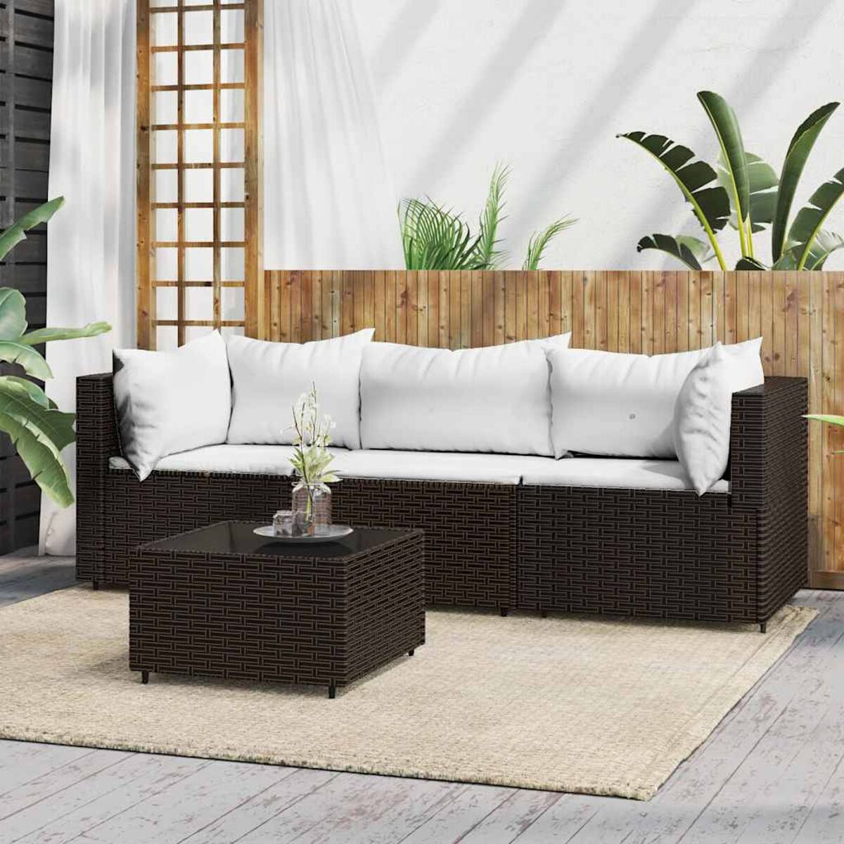 Braunes Rattan-Sofa mit weißen Kissen und einem quadratischen Couchtisch.