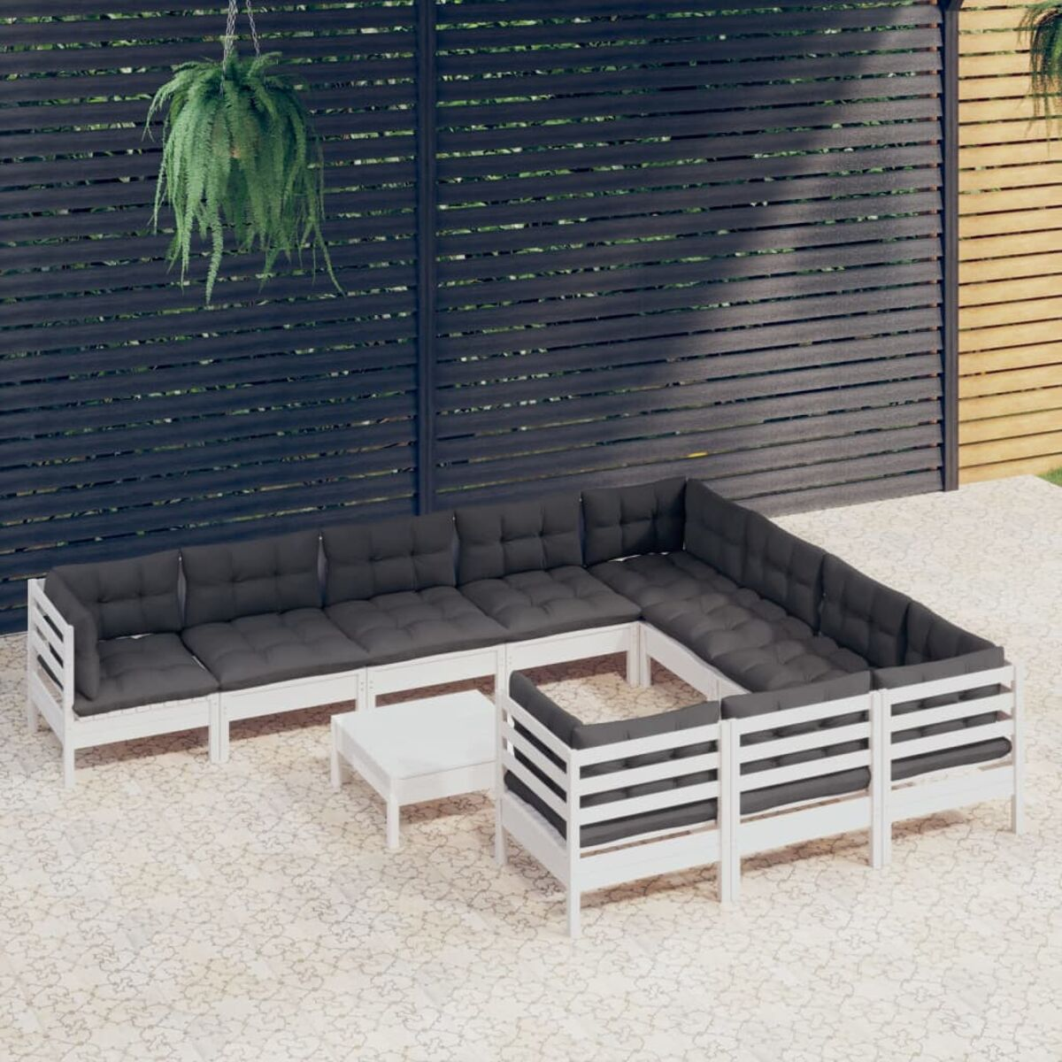Weiße Outdoor-Sitzgruppe aus Holz mit dunkelgrauen Kissen und einem weißen Couchtisch. Draußen auf Beton.