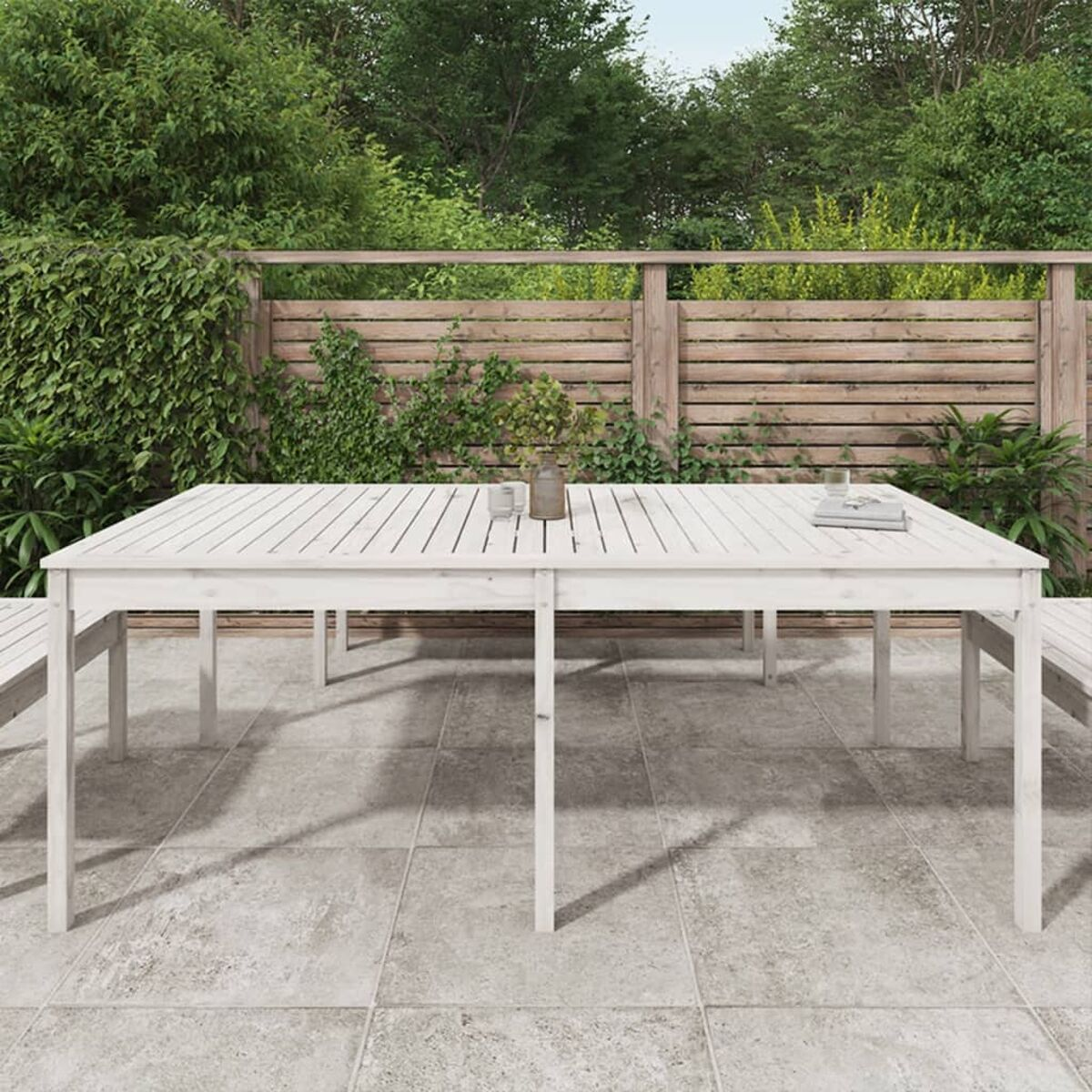 Ein großer, weißer Holztisch mit ein paar Gegenständen, in einer Terrasse im Freien.
