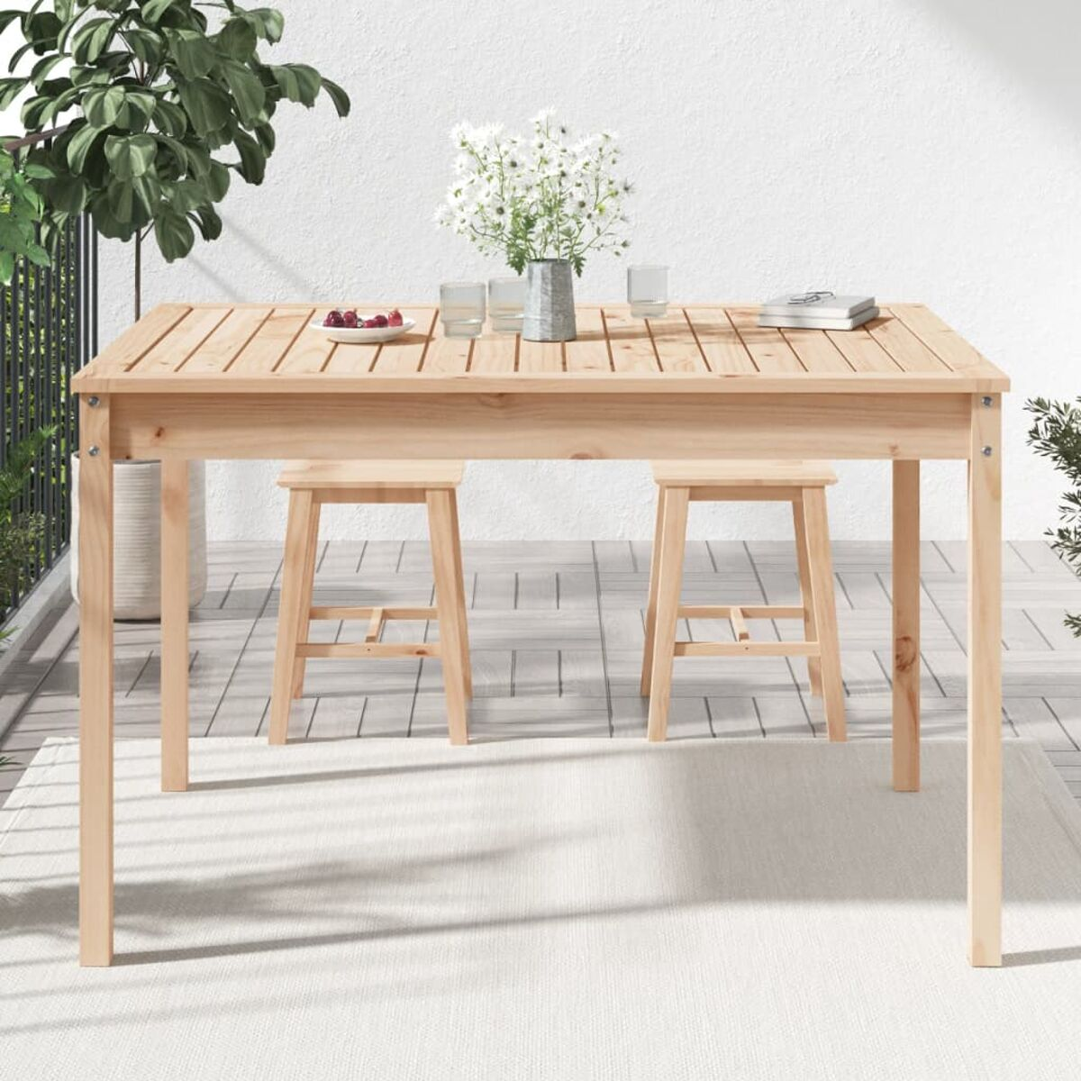 Holztisch mit zwei Hockern. Auf dem Tisch stehen eine Vase mit Blumen und andere Dinge.