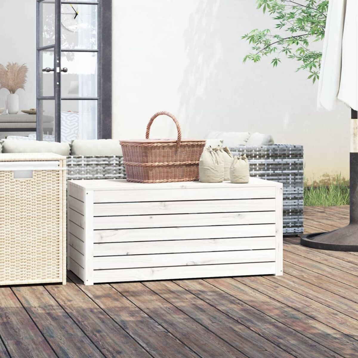 Outdoor-Deck-Szene mit einem Weidenkoffer, Korb und Segeltuchtaschen. Sofa im Hintergrund, Holzterrasse.
