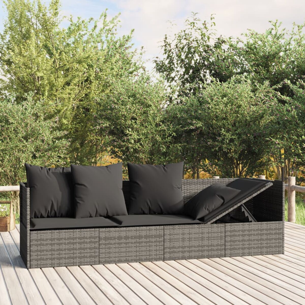 Graues Korbmöbelsofa mit vier dunklen Kissen, auf einem Holzdeck, mit Bäumen im Hintergrund.