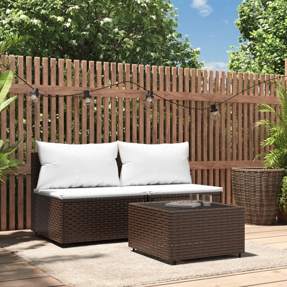Outdoor-Rattansofa-Set mit weißen Kissen. Couchtisch und Pflanzen.