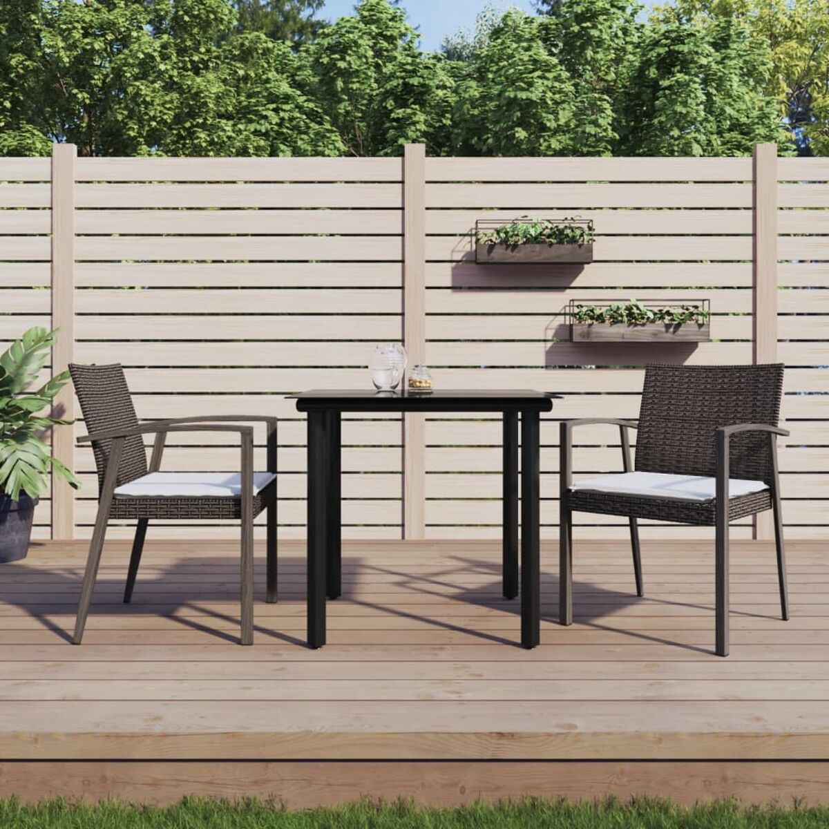Terrassengarnitur auf Holzterrasse mit weißen Kissen. Hintergrund: Zaun und Bäume.