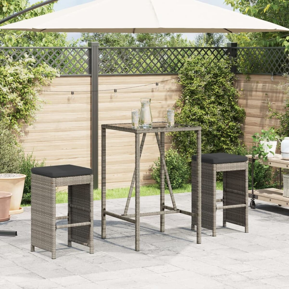Juego de bar al aire libre con dos taburetes, mesa y sombrilla. Muebles de ratán.