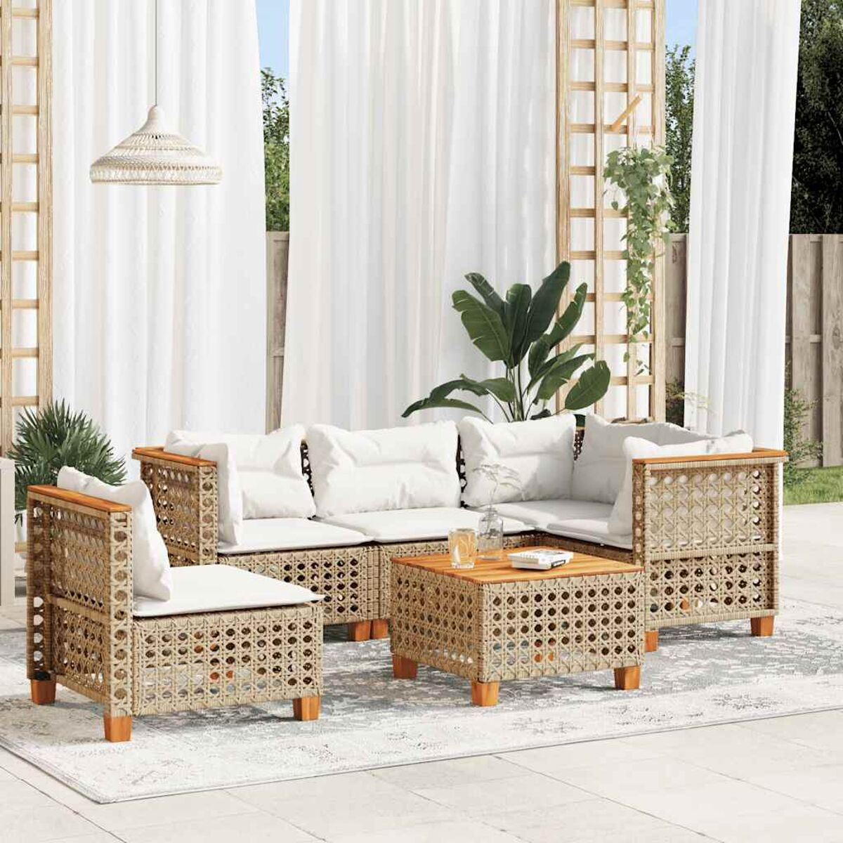 Set di sedute da esterno. Stile rattan. Cuscini bianchi. Tavolo e tende in legno.