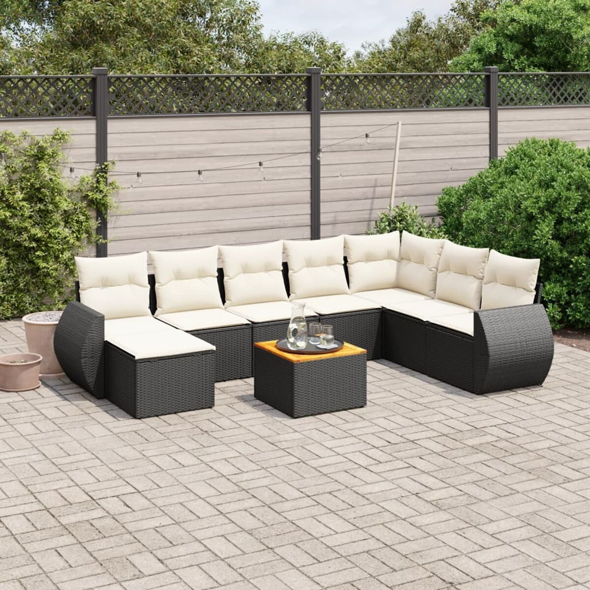 Outdoor-Sofagarnitur mit beigefarbenen Kissen. Schwarzes Korbmuster. Holztisch.