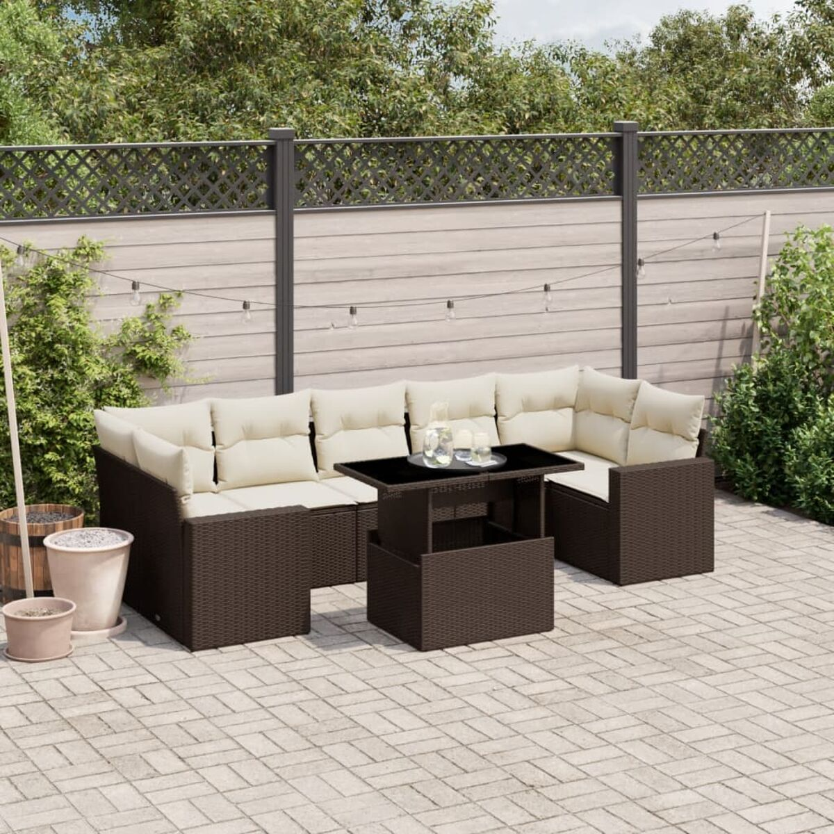 Brauner Outdoor-Eckbereich aus Korbgeflecht mit cremefarbenen Kissen und einem schwarzen Tisch.