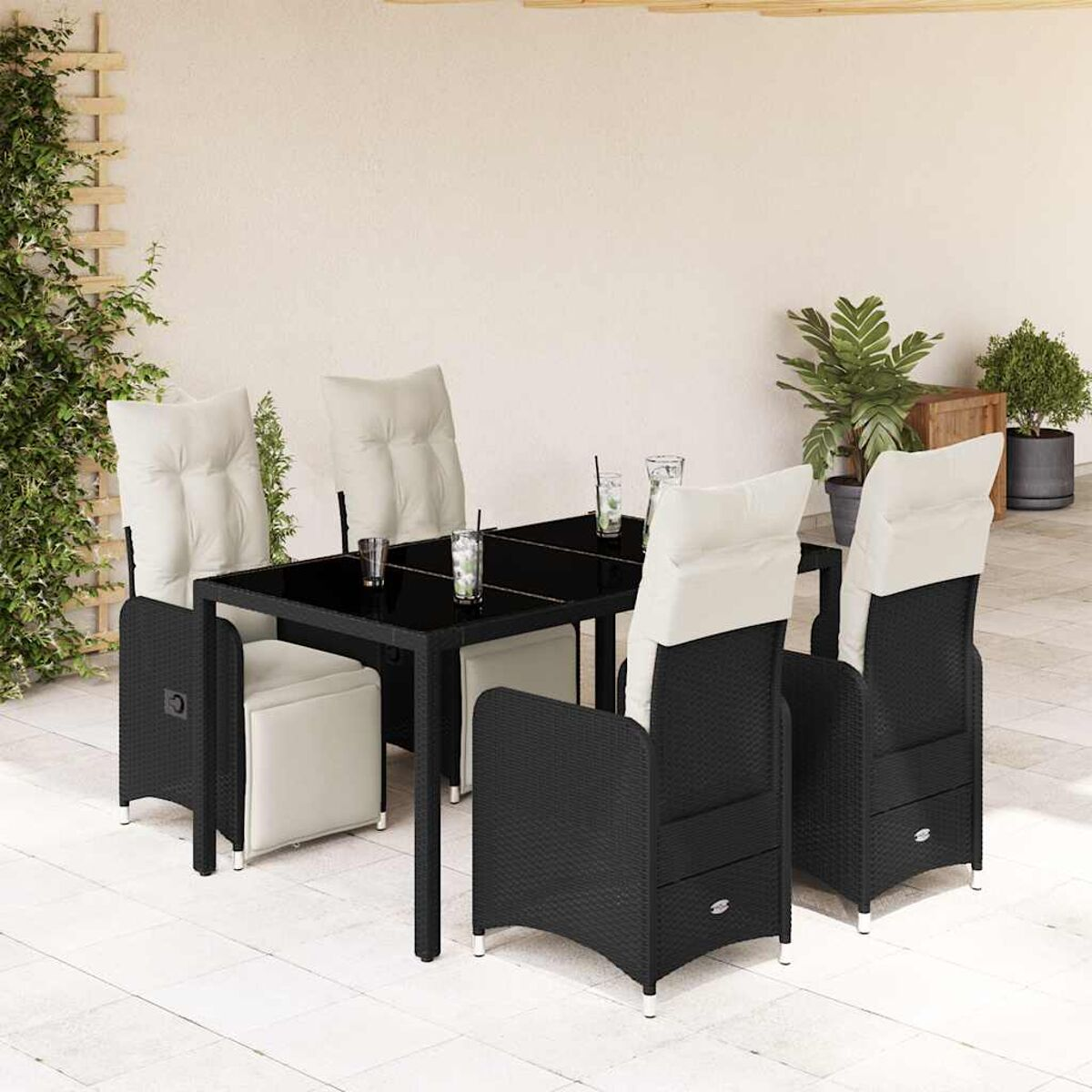 Set da pranzo per esterni con sedie in vimini nere, tavolo in vetro nero e cuscini bianchi.