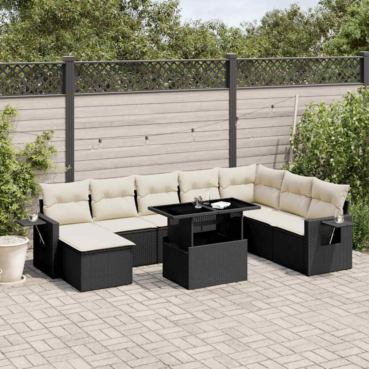 Schwarzes Rattan-Ecksofa mit Lifttisch und Kissen, auf einer Terrasse.